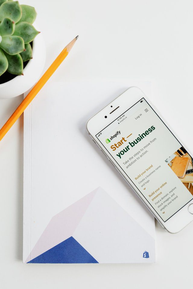 A phone screen reading “Shopify - start your business”