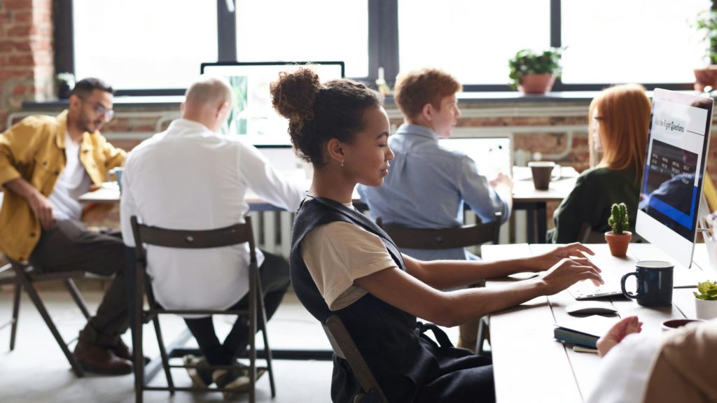 Person sitting at a laptop with a table of people in the background