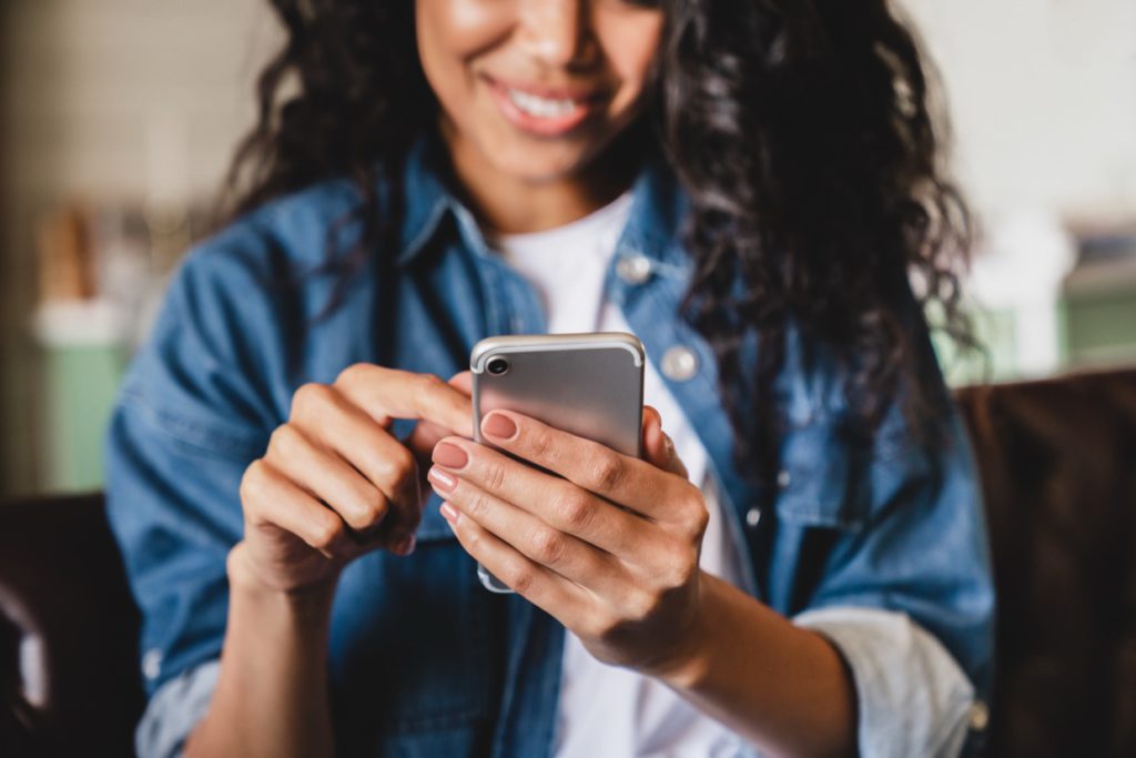 Cropped shot of an african-american young woman using smart phone to QA landing page