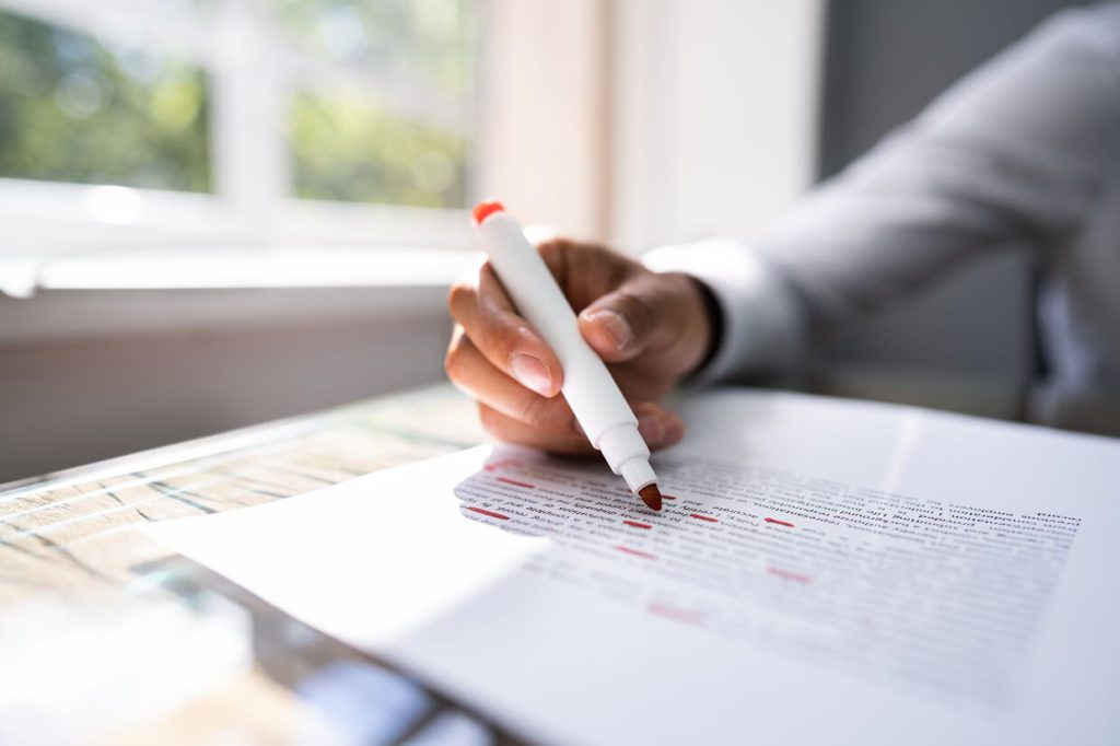 person holding a pen editing copy for web redesign