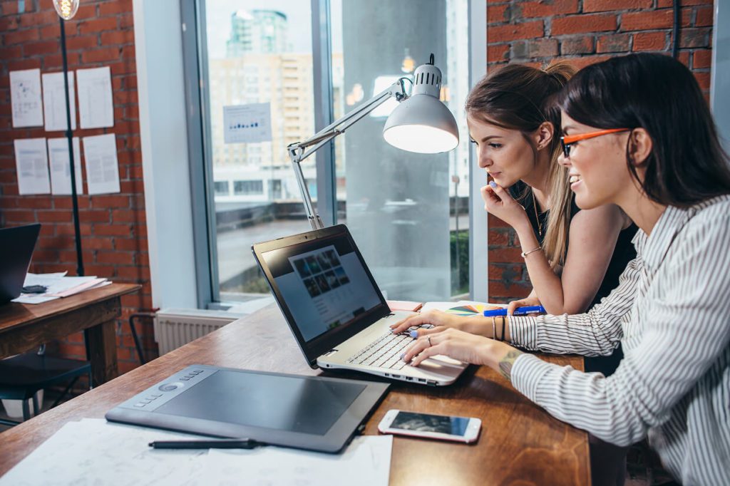 two women in front of the laptop discussing page speed