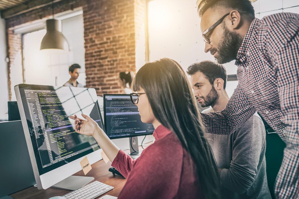 2 males and 1 female gather around a computer screen discussing codes