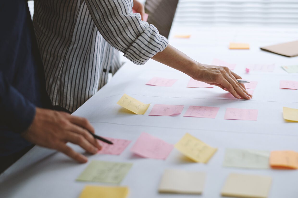 Individuals looking at Post-it Notes on a table
